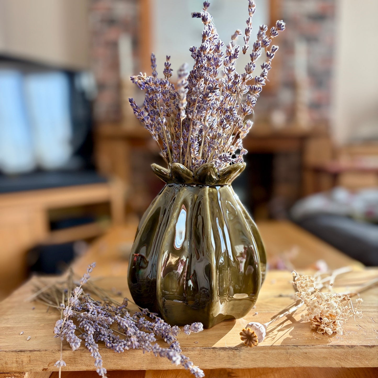 Decorative poppy vase with dried lavender on a wooden surface in a home setting