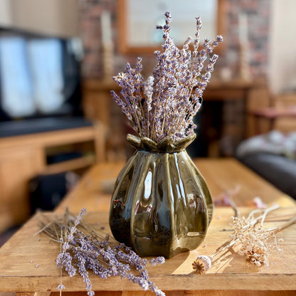 Decorative poppy seed vase with dried lavender on a wooden table in a living room setting.