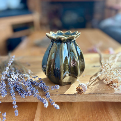 Green poppy seed shaped vase on a wooden surface with dried lavender and flowers.