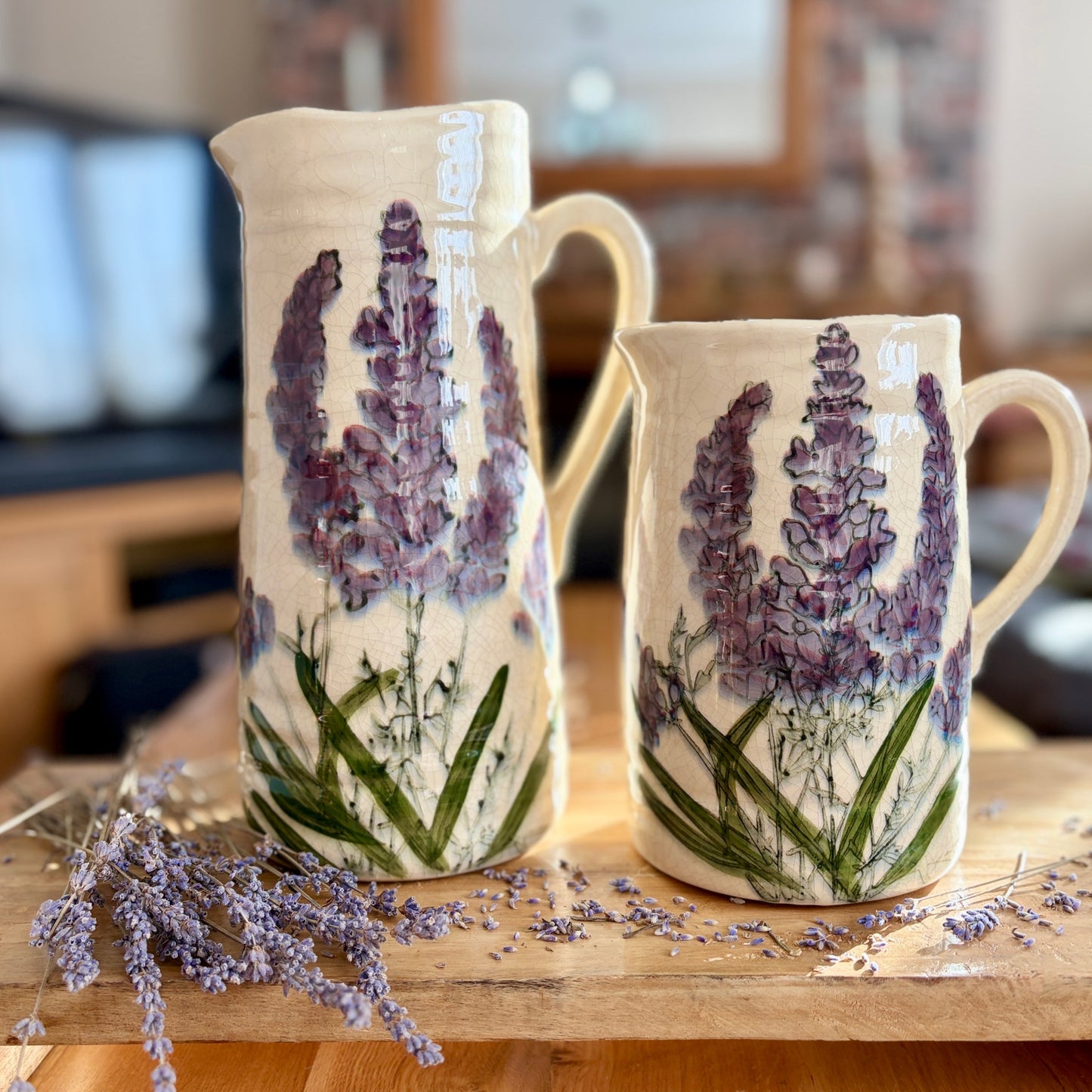 Two ceramic jugs with lavender designs on a wooden surface.