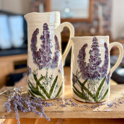 Two ceramic jugs with lavender designs on a wooden surface.