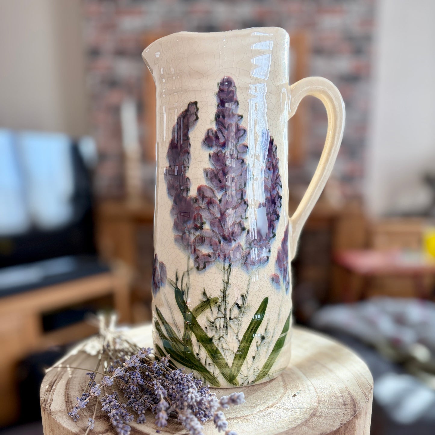 Decorative ceramic jug with floral design on a wooden stool.