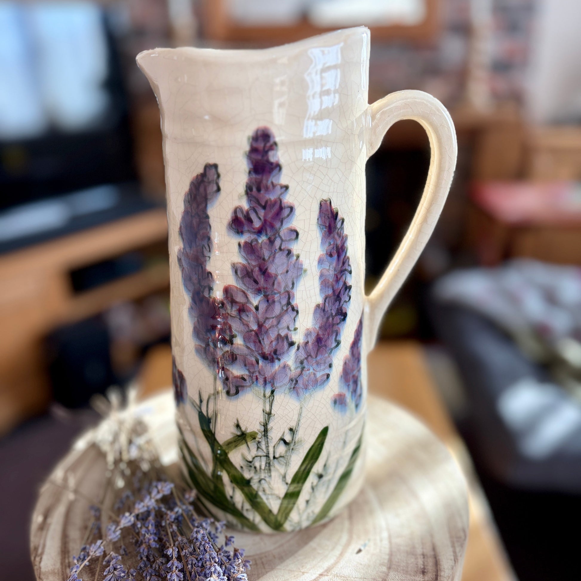 Decorative jug with lavender design on a wooden stool in a home setting
