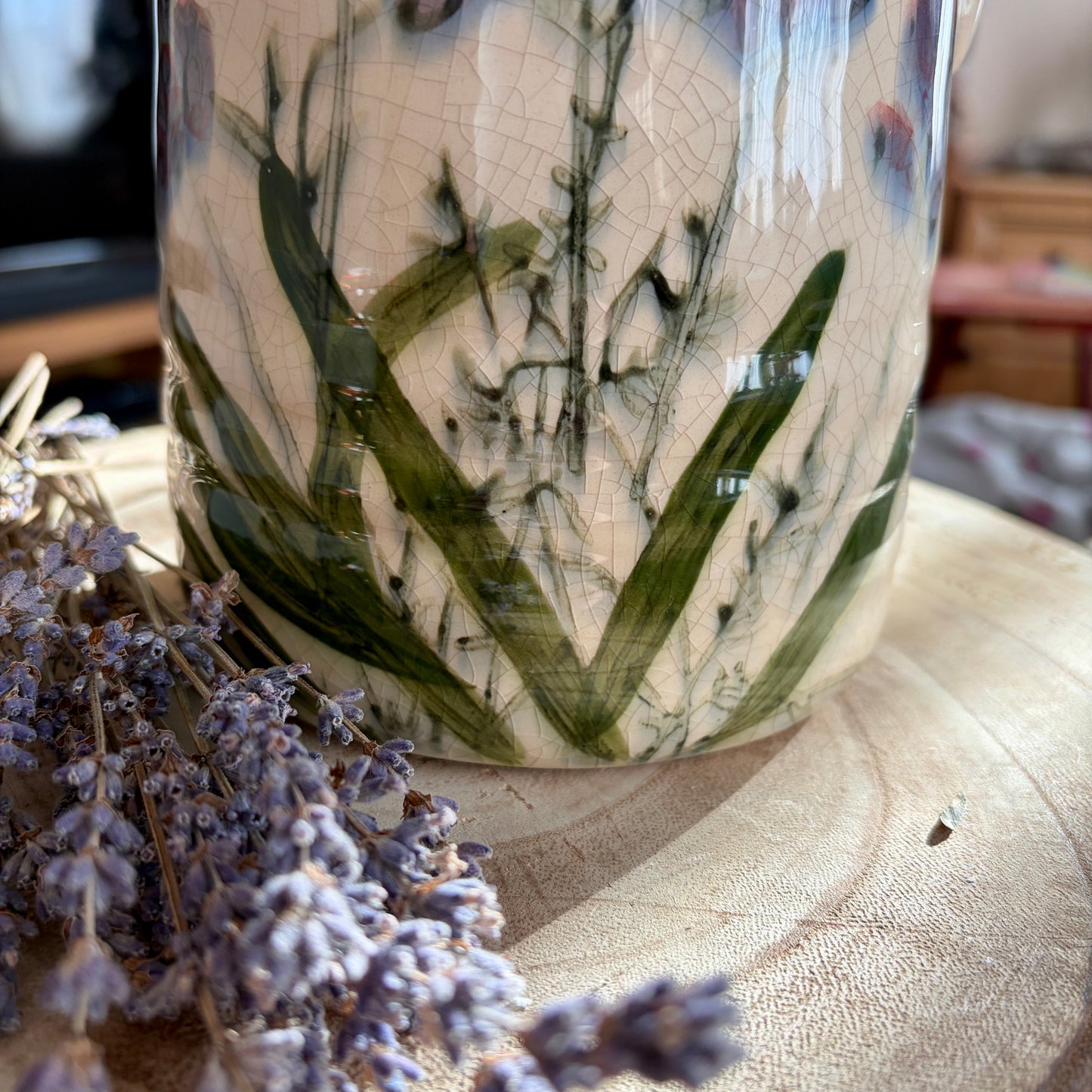 Ceramic vase with floral design on a wooden surface with lavender flowers.