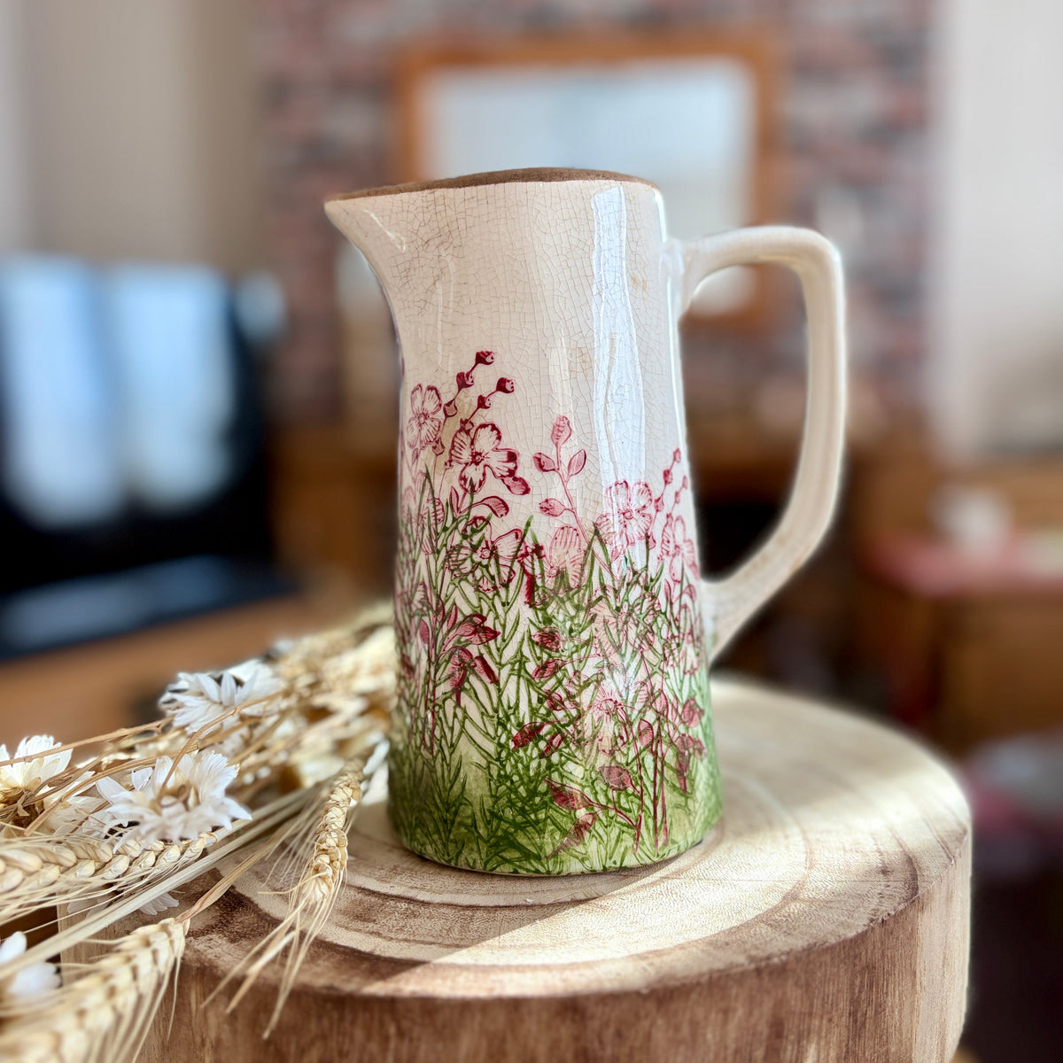 Decorative ceramic jug with floral design on a wooden surface