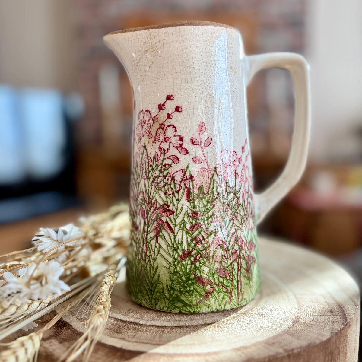 Ceramic jug with floral design on a wooden surface in home setting