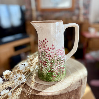 Decorative ceramic jug with floral design on a wooden stool in a home setting