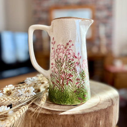 Decorative jug with floral design on a wooden stool in a blurred home setting