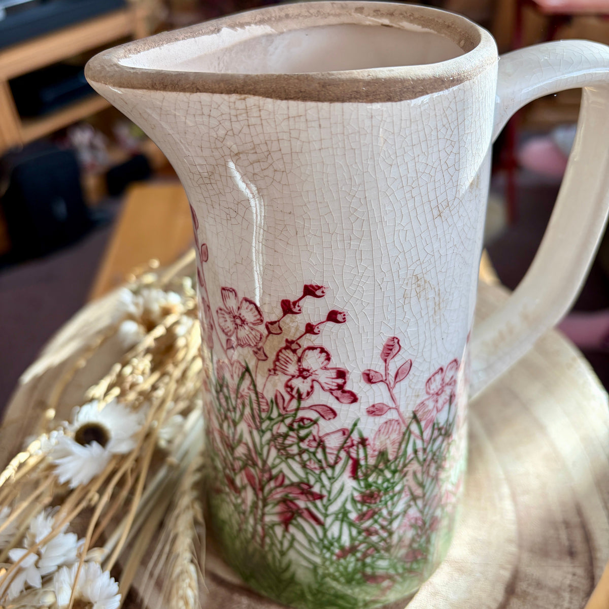 Ceramic jug - top close up - with floral design on a wooden surface