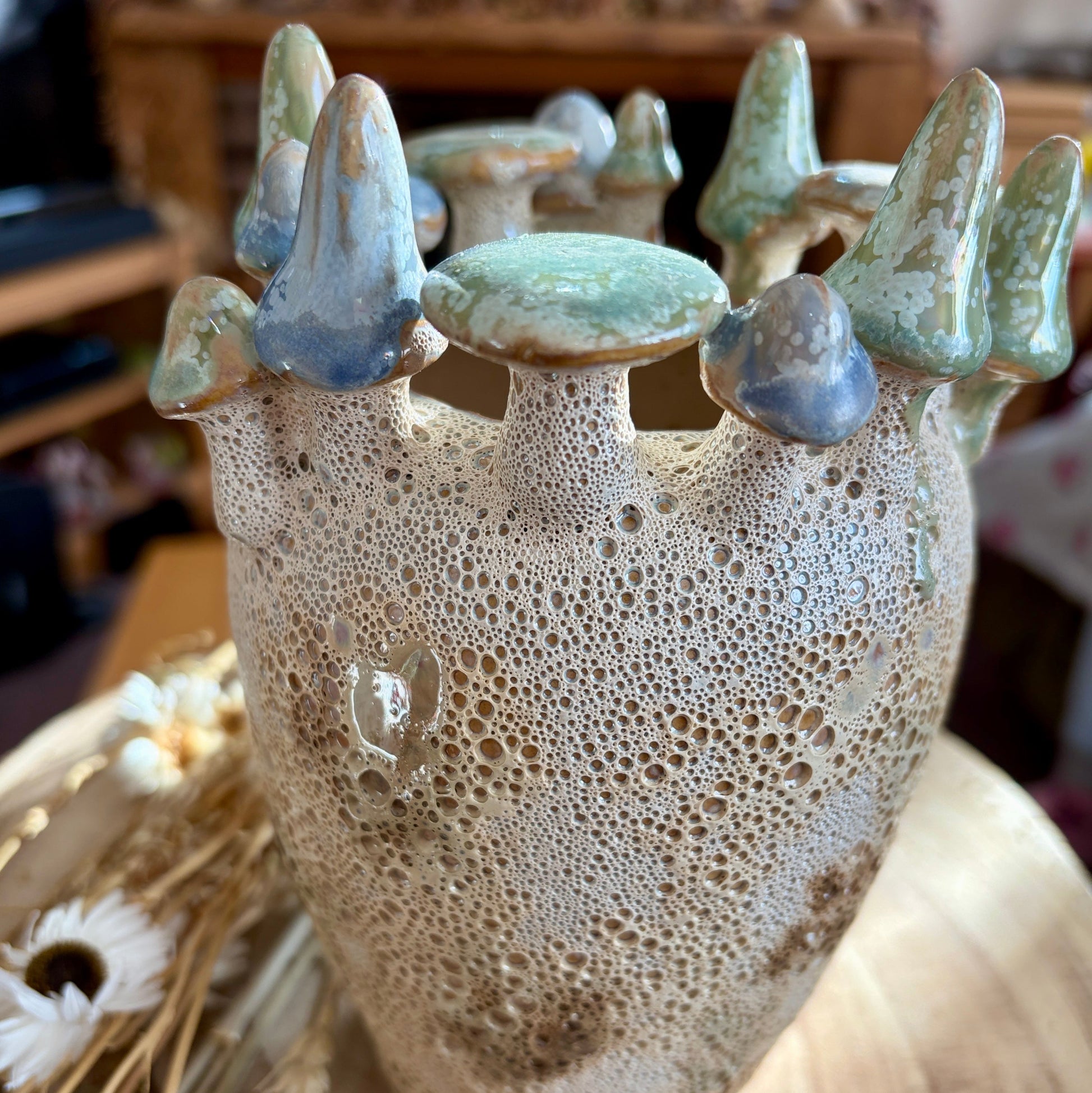 Ceramic vase with textured surface and small decorative toadstools on top