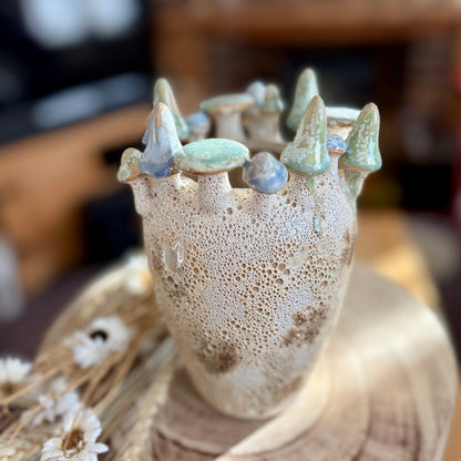 Ceramic vase with textured surface and decorative mushrooms on a wooden surface