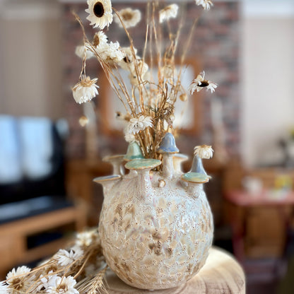 Decorative vase with dried flowers on a wooden surface in a blurred home setting