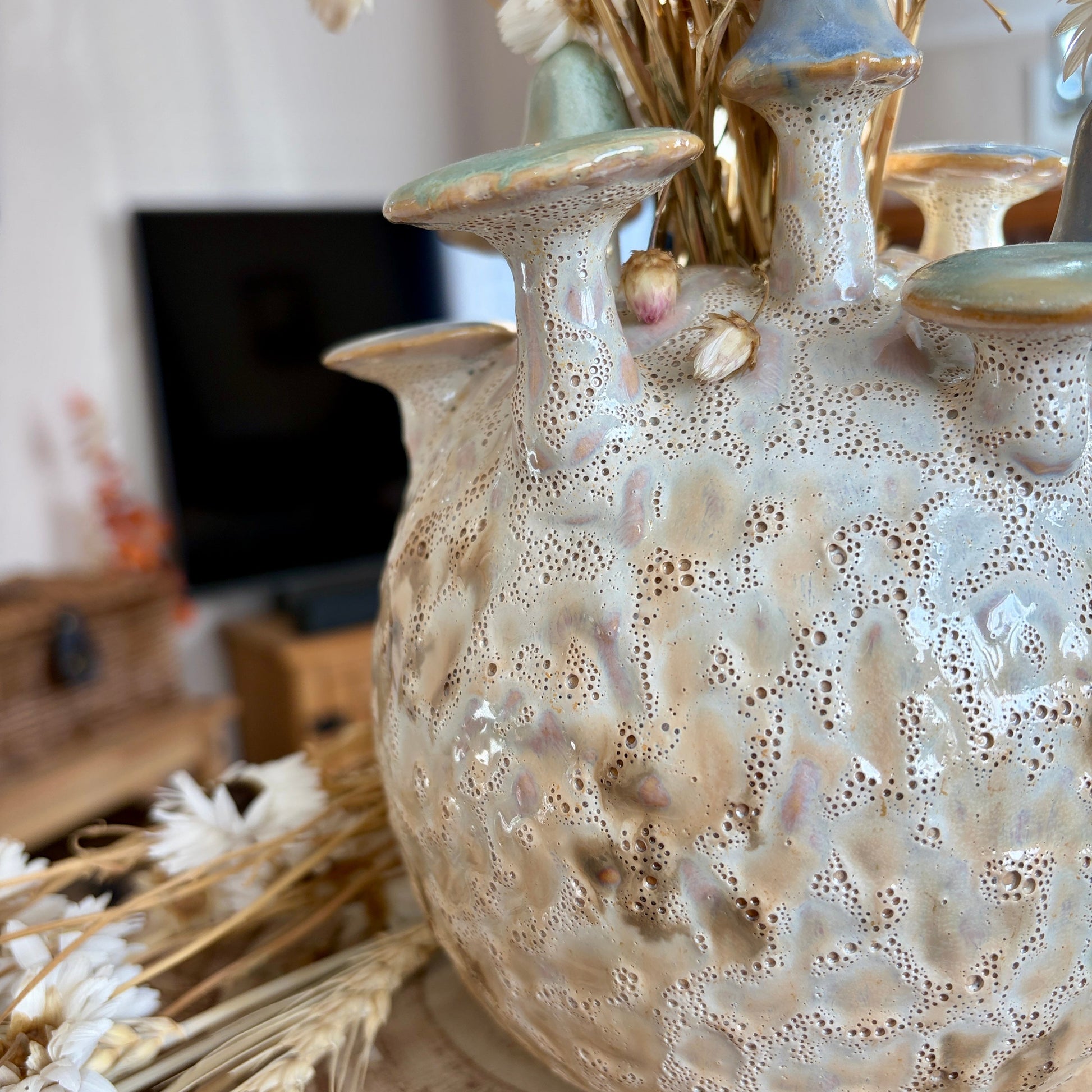 Textured ceramic vase with mushroom design on a surface with blurred background