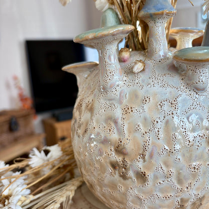 Textured ceramic vase with mushroom design on a surface with blurred background