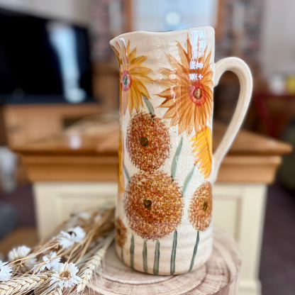 Decorative ceramic jug with floral design on a wooden stool in a home setting