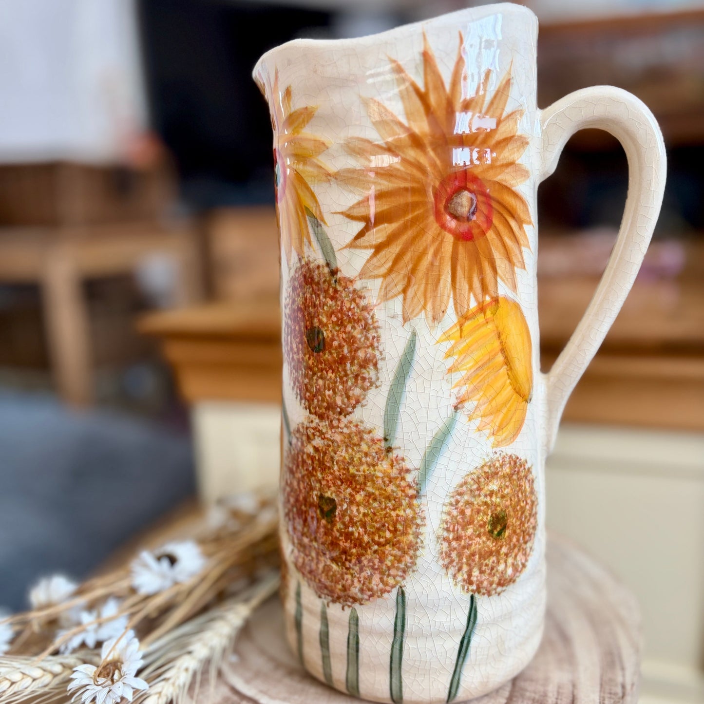 Decorative jug with sunflower design on a wooden surface
