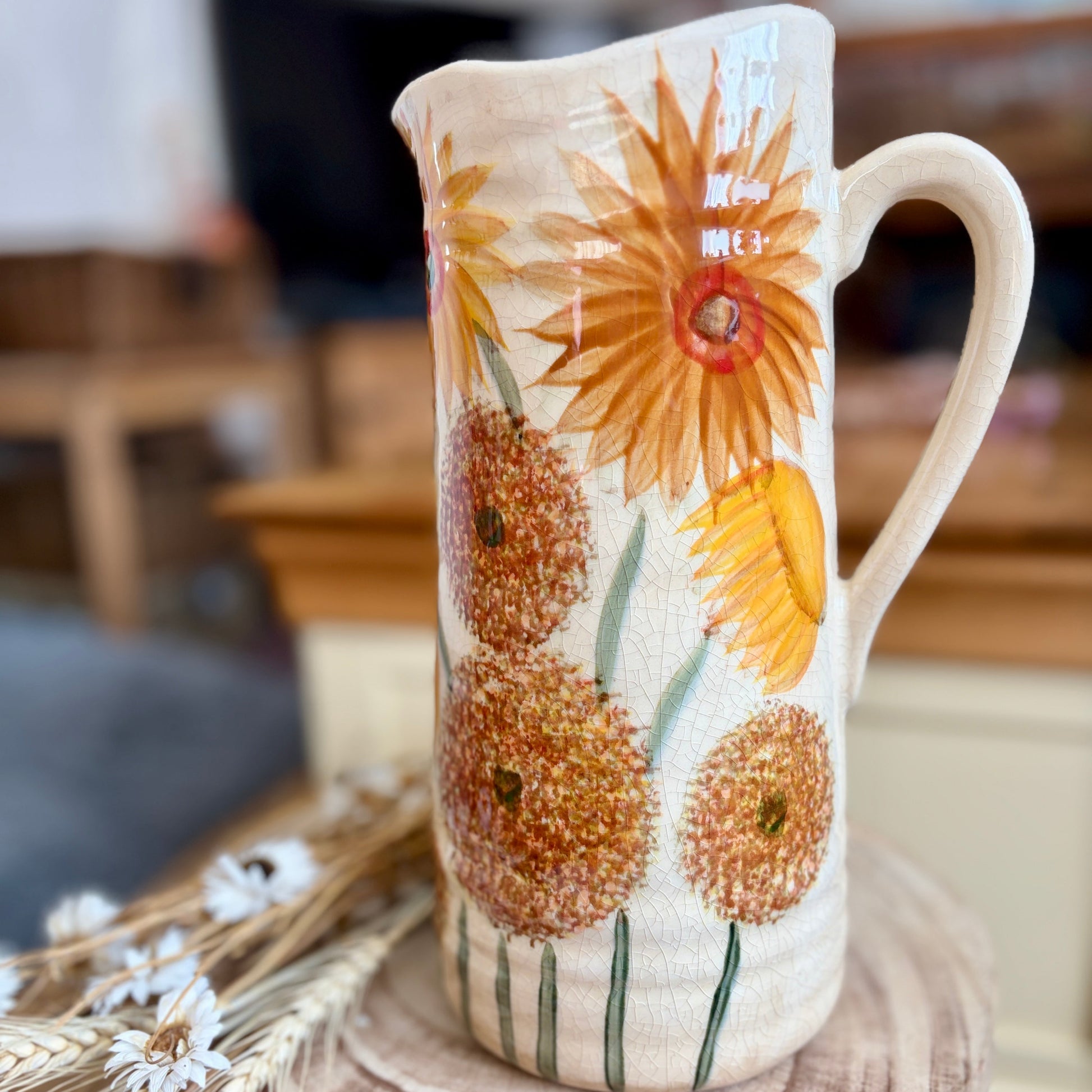 Decorative jug with sunflower design on a wooden surface