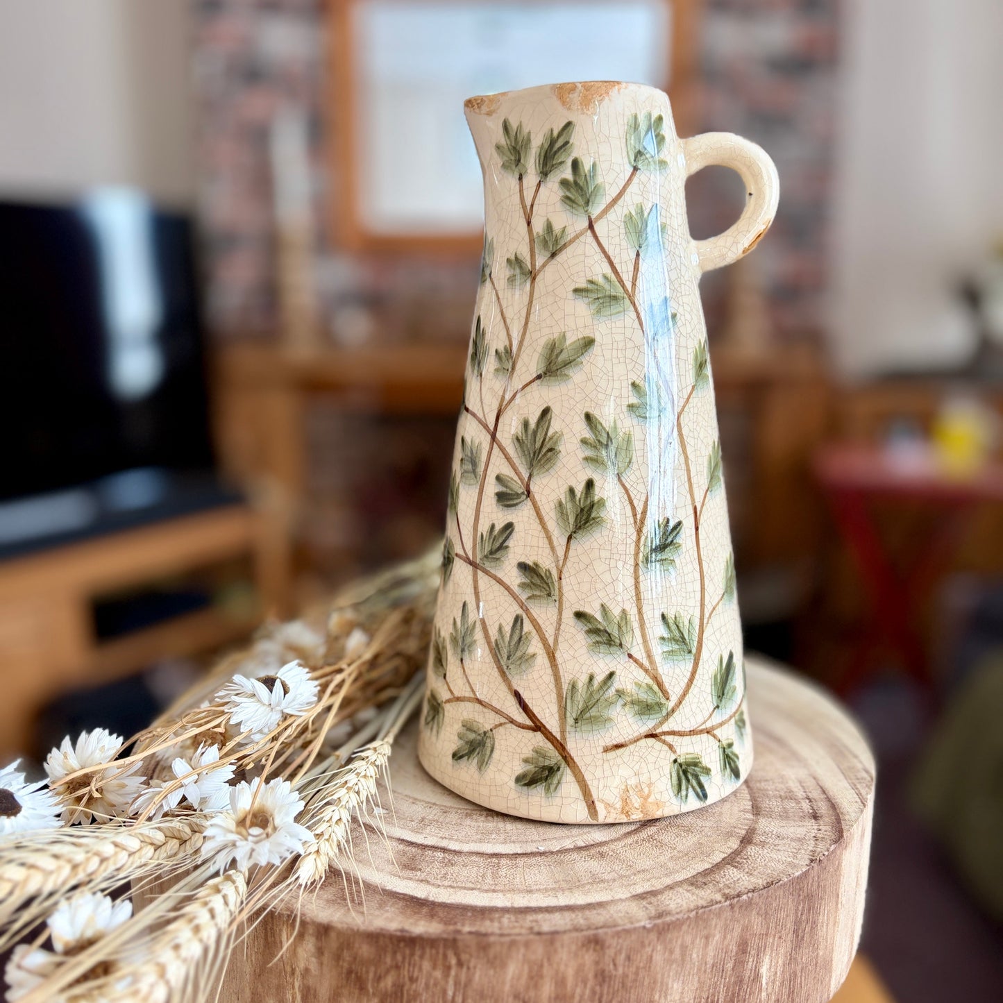 Decorative vase with floral patterns on a wooden stool in a home setting