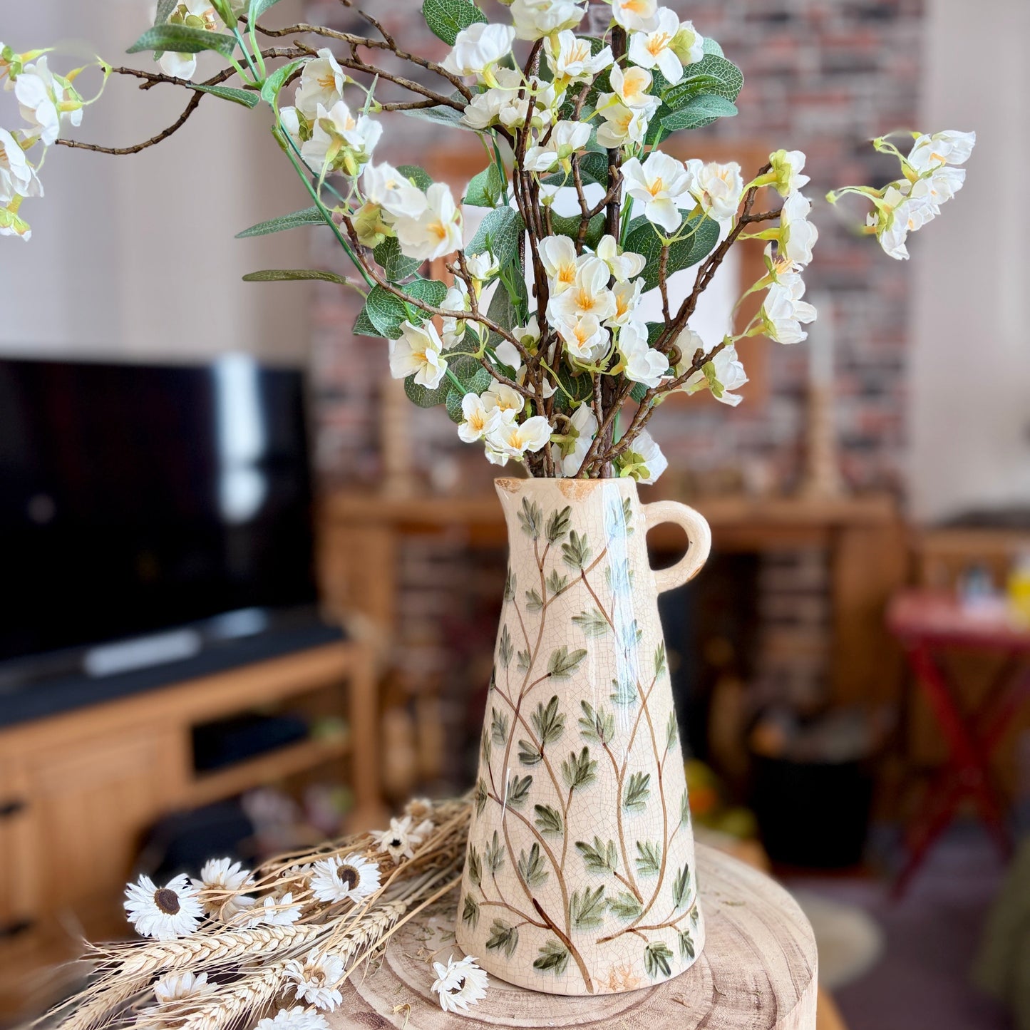 Decorative vase with flowers inside on a wooden stool in a room setting