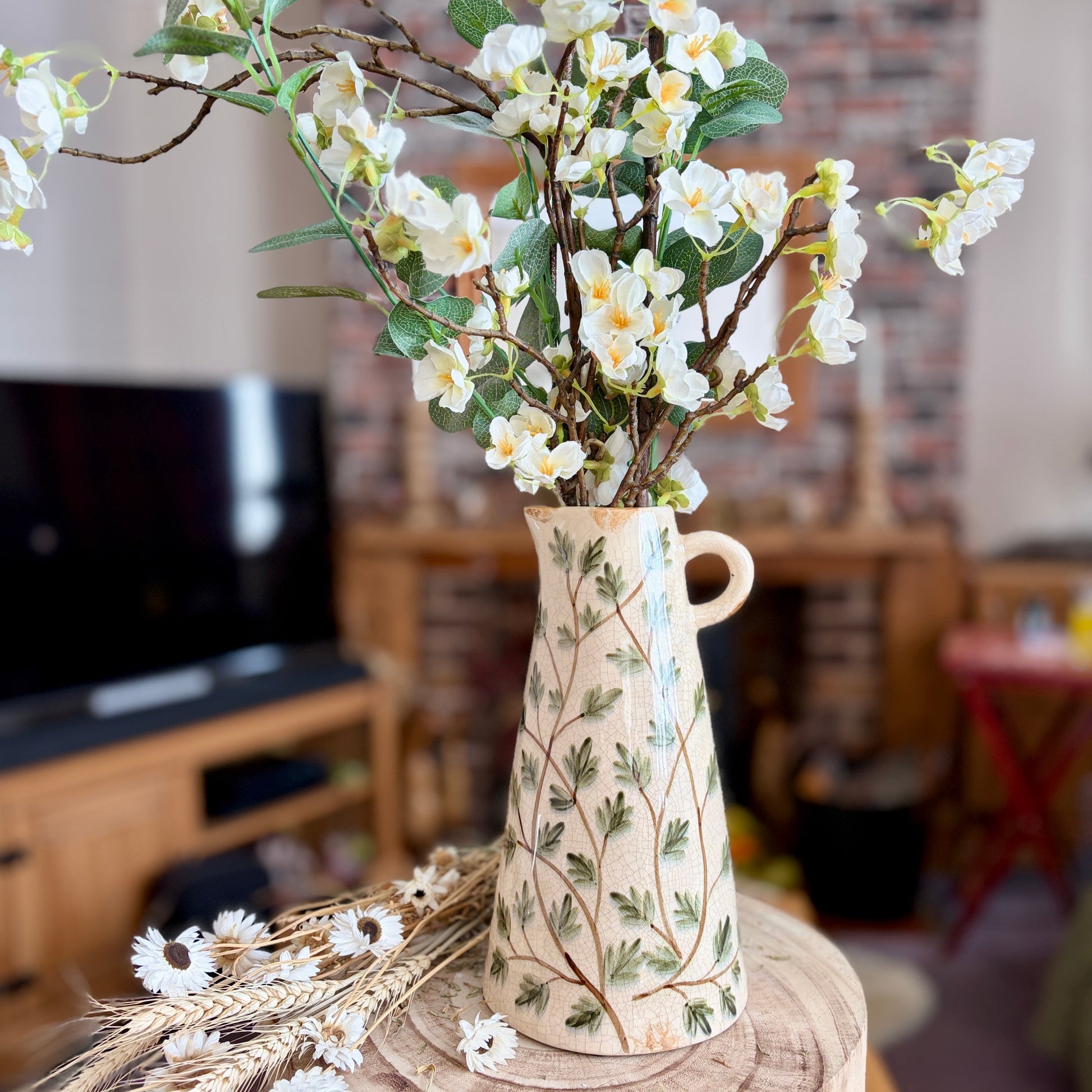Decorative vase with flowers inside on a wooden stool in a room setting