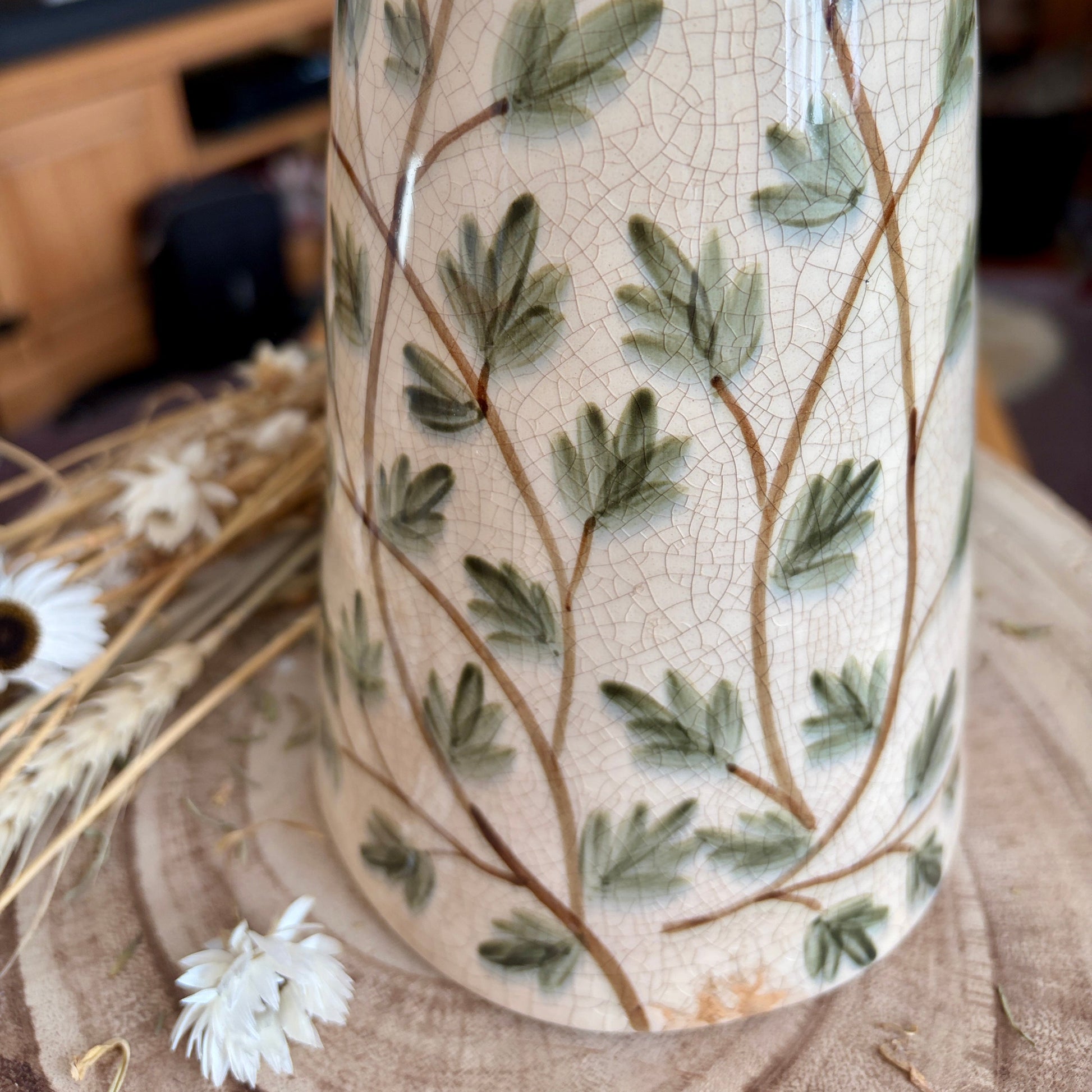 Close up crackle effect on a decorative vase with leaf pattern on a wooden surface