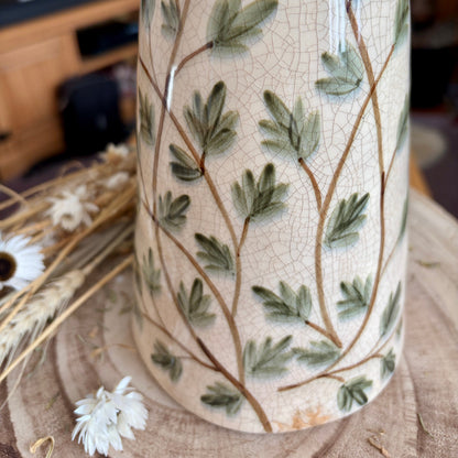 Close up crackle effect on a decorative vase with leaf pattern on a wooden surface
