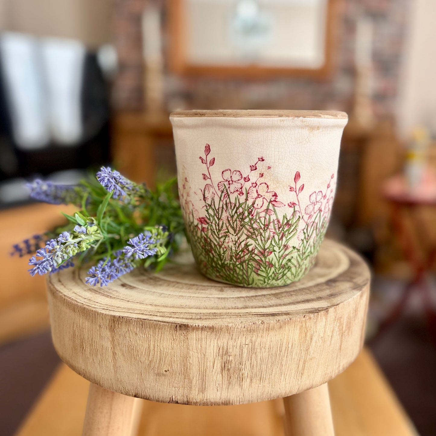 Stoneware plant pot with floral design sat next to a bunch of lavender in a home setting.
