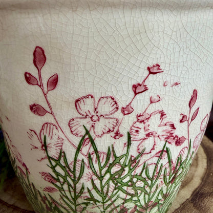 Close up of the crackle effect on a ceramic floral plant pot on a wood base.