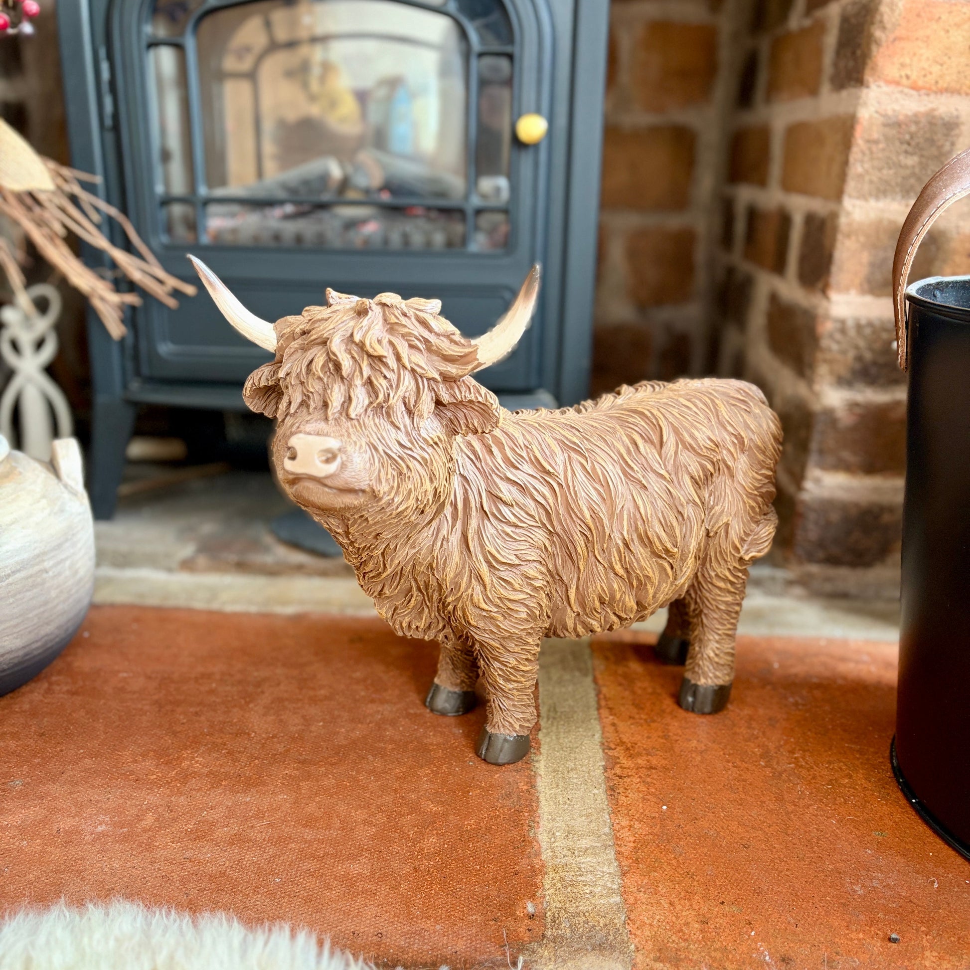 Statue of a Highland cow in front of a fireplace