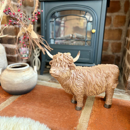 Statue of a Highland cow in front of a fireplace with decorative elements.