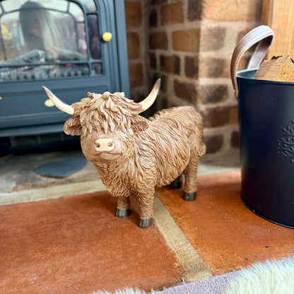 Statue of a Highland cow on a hearth with a fireplace in the background