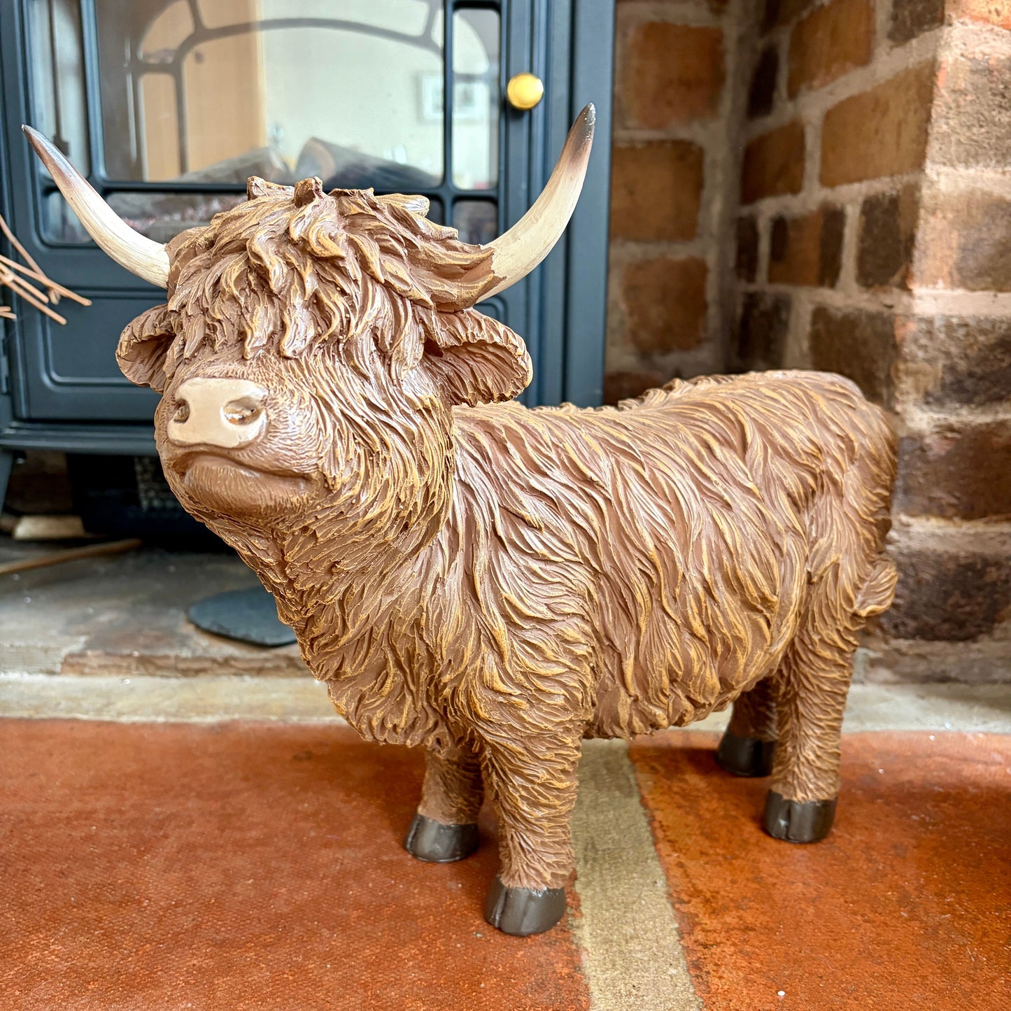 Large statue of a highland cow in front of a fireplace.