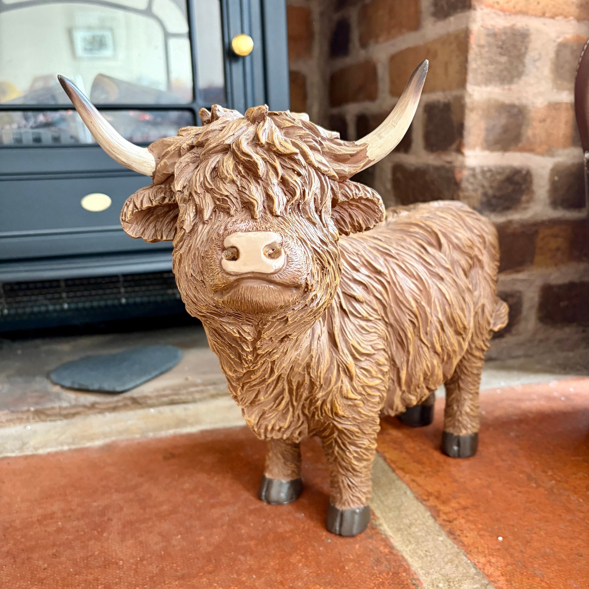 Large sculpture of a highland cow in front of a fireplace.