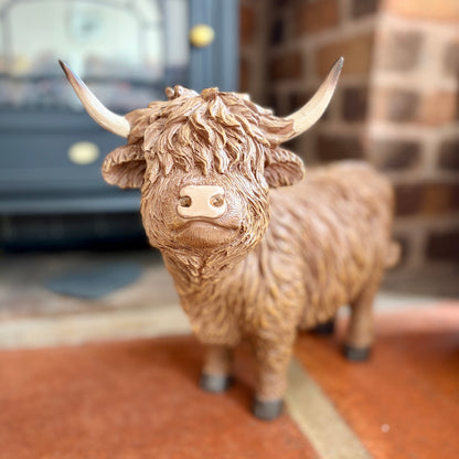 Large statue of a Highland cow on a slabbed floor with a blurred background