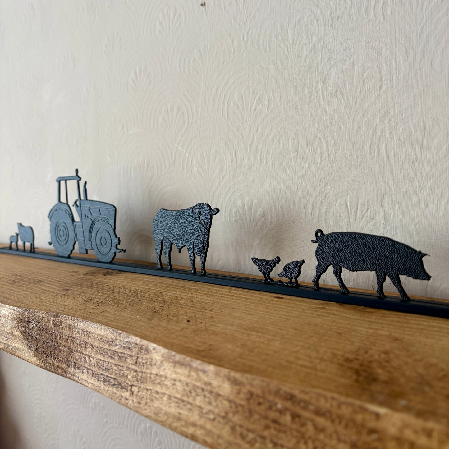 Decorative shelf with recycled plastic animal silhouettes on a wooden ledge against a white wall.