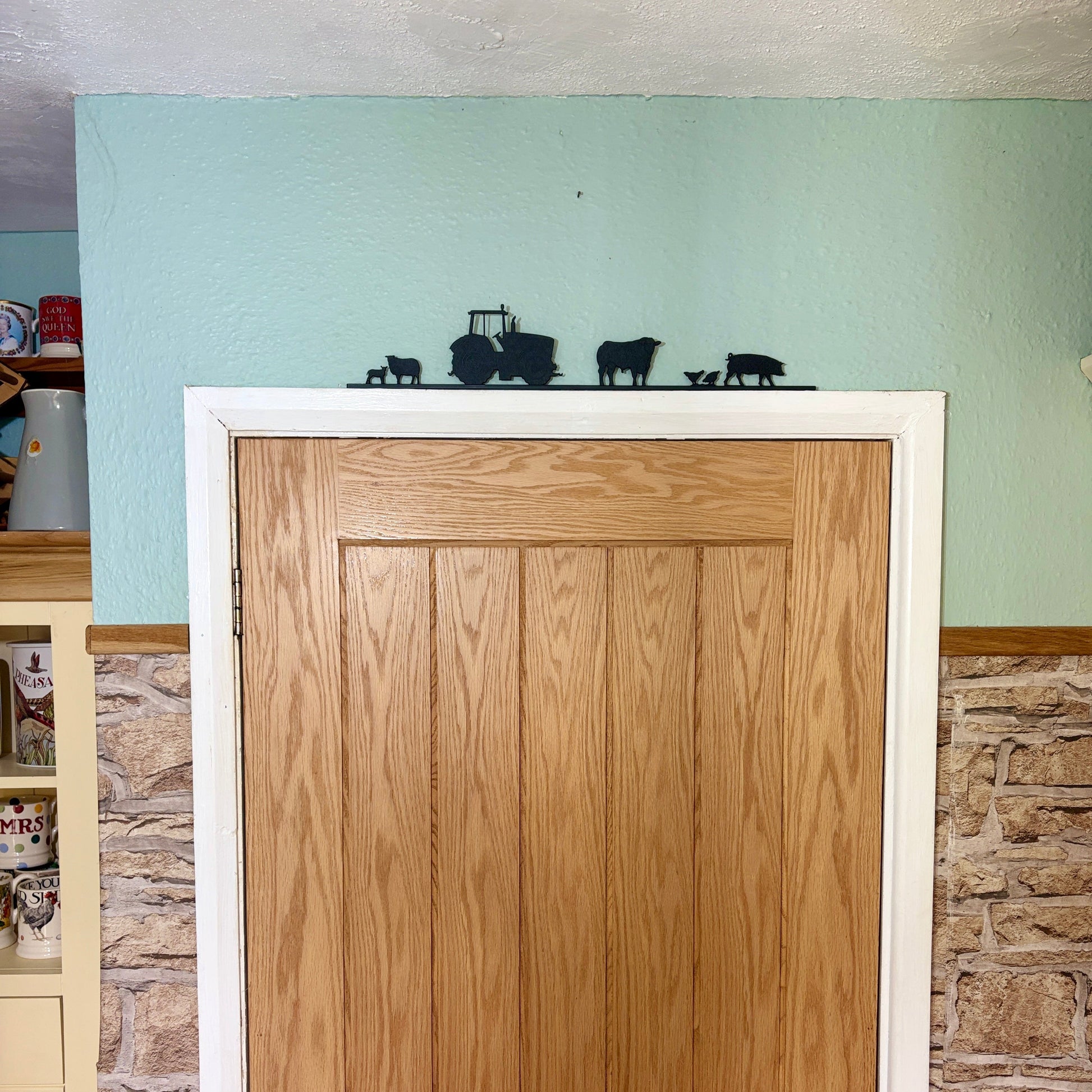 Wooden door with white frame with recycled plastic decoration of tractor and farm animal silhouettes.