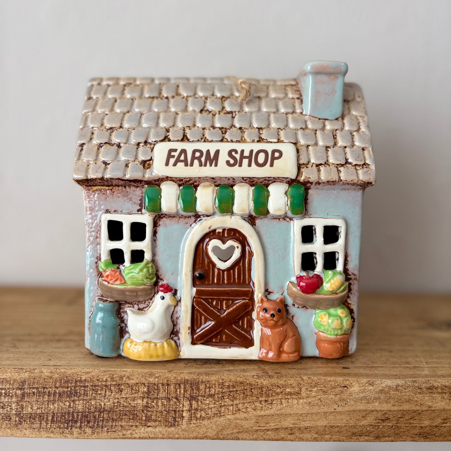 Decorative ceramic farm shop candle holder on a wooden surface with a plain background