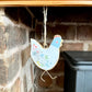 Metal Chicken Hanger Displayed by Fireplace