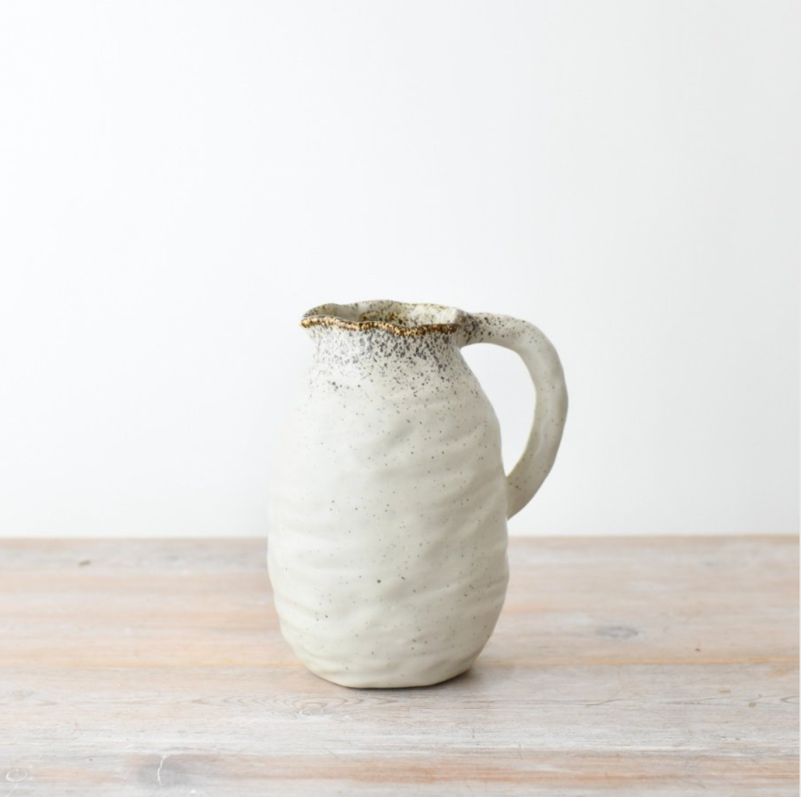 Ceramic jug with speckled design on a wooden surface