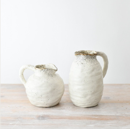 Two ceramic jugs on a wooden surface with a white background